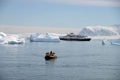 20A Zodiac Coming In To Land On Cuverville Island With Brabant Island And The Quark Expeditions Antarctica Cruise Ship Beyond.jpg